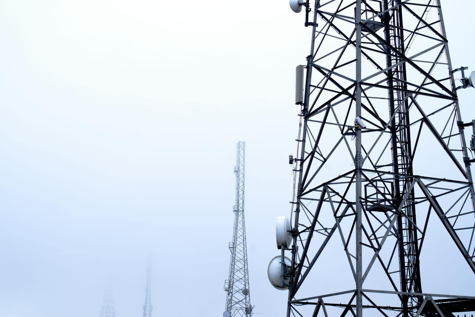 Tours de télécommunication équipées d'antennes hertziennes dans la brume.