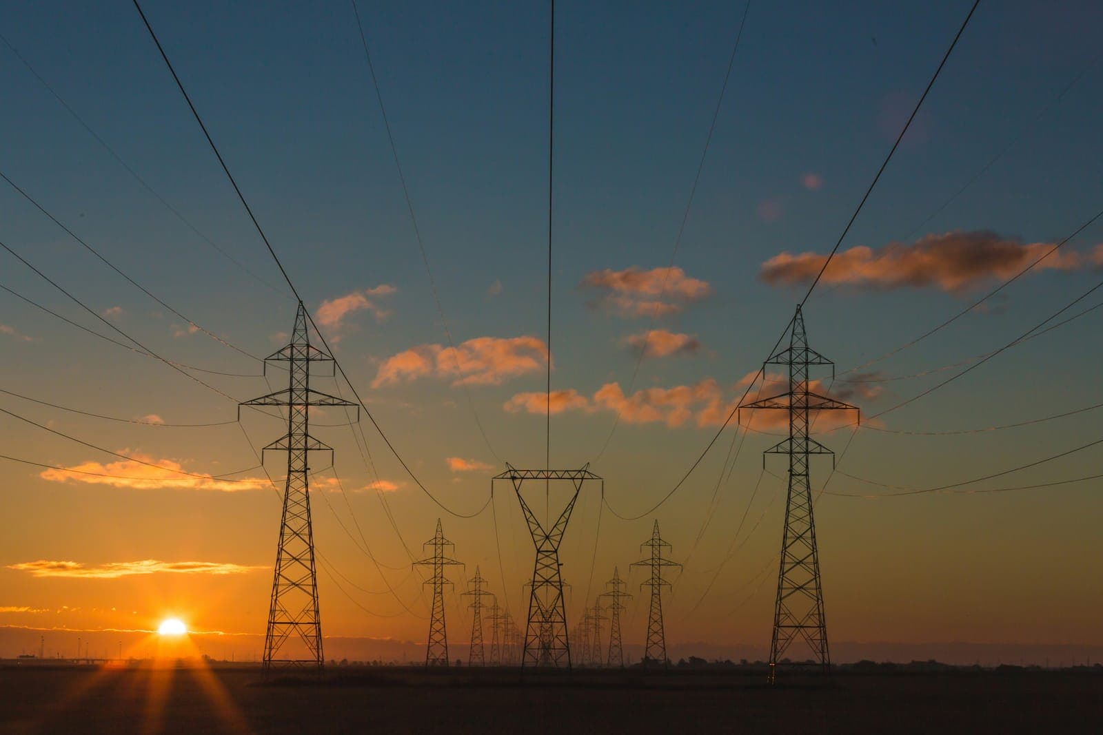 Lignes de transport à haute tension et pylônes électriques au coucher du soleil.