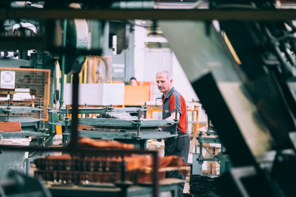 Opérateur en atelier de production réglant une machine-outil sur une ligne de fabrication.